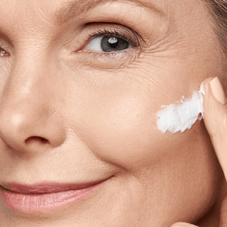 Femme appliquant délicatement une crème, mettant en évidence la routine de soin ciblée pour les signes de vieillissement de la peau liés à la ménopause.