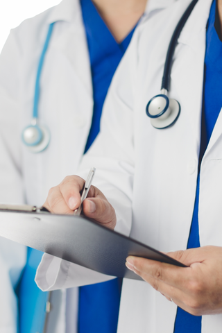 Professionnels de la santé en blouses blanches, stéthoscope en évidence, écrivant sur un presse-papiers, symbolisant le soin médical et l'expertise clinique.